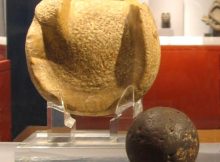 A solid rubber ball used (or similar to those used) in the Mesoamerican ballgame, 300 BCE to 250 CE, Kaminaljuyu. The ball is 3 inches (almost 8 cm) in diameter, a size that suggests it was used to play a handball game. Behind the ball is a manopla, or handstone, which was used to strike the ball, 900 BCE to 250 CE, also from Kaminaljuyu. Image credit: Wikipedia