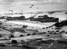 Landing ships putting cargo ashore on Omaha Beach, at low tide during the first days of the operation, mid-1944-06 Among identifiable ships present are LST-532 (in the center of the view); USS LST-262 (3rd LST from right); USS LST-310 (2nd LST from right); USS LST-533 (partially visible at far right); and USS LST-524. Note barrage balloons overhead and Army "half-track" convoy forming up on the beach. The LST-262 was one of 10 Coast Guard-manned LSTs that participated in the invasion of Normandy, France.